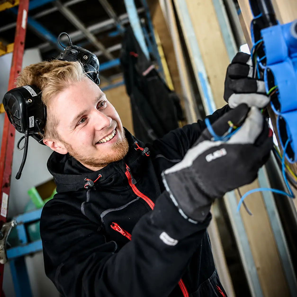 Leende elektriker vid blå kopplingsdosa